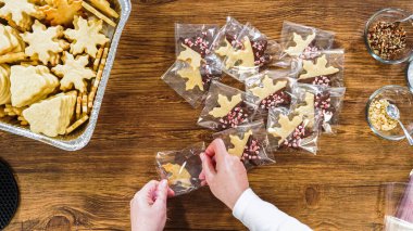 Düz yatıyordu. Dikkatlice paketlenmiş Noel kurabiyeleri, çikolataya batırılmış, ezilmiş fındık serpiştirilmiş, ve şeffaf selofan ambalajla sunulmuş..