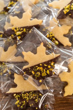 Dikkatlice paketlenmiş Noel kurabiyeleri, çikolataya batırılmış ve şeffaf selofan ambalajla sunulmuş, bayram hediyesi olarak mükemmel..