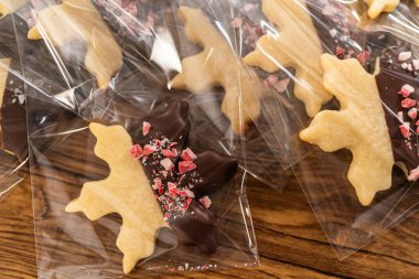 Dikkatlice paketlenmiş Noel kurabiyeleri, çikolataya batırılmış ve şeffaf selofan ambalajla sunulmuş, bayram hediyesi olarak mükemmel..