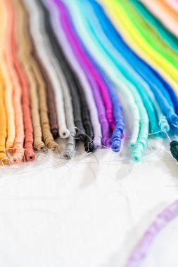 Beyaz bir masadaki renklere göre düzenlenmiş canlı bir kil boncuk koleksiyonu genç zanaatkarlara kendi eşsiz bileziklerini yapmaları için ilham vermeye hazır..