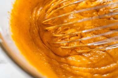 Ağız sulandırıcı ev yapımı balkabağı pastası için büyük bir karıştırma kabında ustalıkla harmanlanmış malzemelerin yakın çekimi..