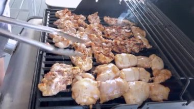 Salamura edilmiş tavuk butları küçük bir Weber ızgarasının ızgarasında cızırdar, havayı iştah açıcı bir koku ve hafif bir dumanla doldurur..