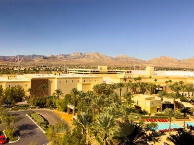 Las Vegas, Nevada, ABD-08 Kasım 2024 Las Vegas 'taki Red Rock Resort' un lüks havuz manzarası, uzun palmiye ağaçları ve canlı kırmızı şezlonglar tarafından çerçevelenmiş. Sakin mavi havuzlar ve