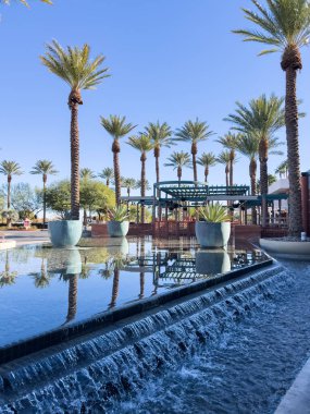 Las Vegas, Nevada, ABD-Kasım 09, 2024 Red Rock Resort 'ta zarif bir açık hava alanı. Uzun, görkemli palmiye ağaçları ve huzur verici bir yansıtıcı havuzu var. Kristal berrak su palmiyeyi yakalar.