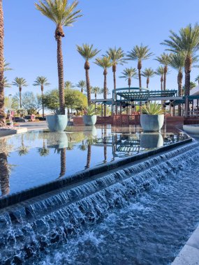 Las Vegas, Nevada, ABD-Kasım 09, 2024 Red Rock Resort 'ta zarif bir açık hava alanı. Uzun, görkemli palmiye ağaçları ve huzur verici bir yansıtıcı havuzu var. Kristal berrak su palmiyeyi yakalar.
