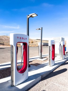 Kunduz, Utah, ABD-10 Kasım 2024, Tesla Supercharger 'a bağlı bir Tesla Cybertruck' ın yakın plan görüntüsü açık arazinin manzaralı arka planına ve parçalı bulutlu gökyüzüne karşı. İnce çizgiler.