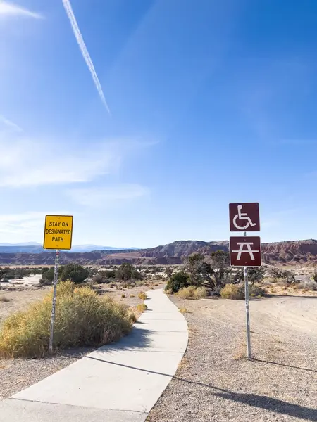 Green River, Utah, ABD-10 Kasım 2024 - San Bench View Area 'daki ulaşılabilir bir patika parlak mavi gökyüzü altında manzaralı bir çöl manzarası boyunca esiyor. Bilgilendirme işaretleri belirlenen yolu işaretler