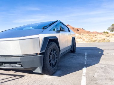 Green River, Utah, USA-November 10, 2024-A Tesla Cybertruck is parked at the San Bench View Area, standing out against a backdrop of rugged red rock formations under a vibrant blue sky. The futuristic clipart