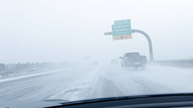 Denver, Colorado, USA-January 15, 2024-Several vehicles face blinding snowfall and slippery conditions while traveling on an interstate, with the storm reducing visibility and the road boundaries clipart