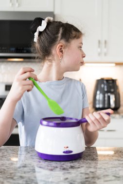 Odaklanmış bir dikkatle, bu filizlenen aşçılık sanatçısı krakerleri erimiş çikolataya batırarak iyi aydınlatılmış bir ev mutfağının sıcaklığında tatlı tatlar yaratıyor..