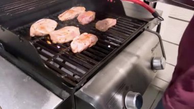 Denver, Colorado, ABD-25 Şubat 2024 marinelenmiş domuz pirzolası Weber gaz ızgarasının ızgarasında cızırdıyor ve açık hava yemeklerinin dumanlı özünü emiyor. Izgaralar yüksek sıcaklıkta kapanıyor.