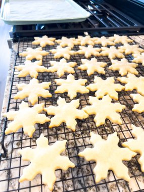 Başlık: Taze pişmiş kar tanesi şekerli kurabiyeler serinletici betimleme: Modern bir mutfaktaki tel askıda soğuyan kar tanesi şeklinde şekerli kurabiyeler. Mükemmel pişmiş ve tatil dekorasyonu için hazır.