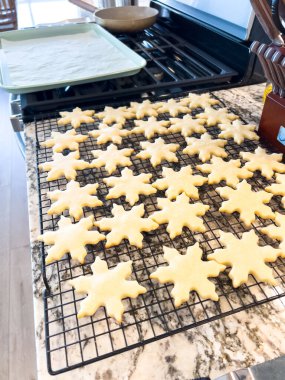 Title: Freshly Baked Snowflake Sugar Cookies Cooling Description: A batch of snowflake-shaped sugar cookies cooling on a wire rack in a modern kitchen. Perfectly baked and ready for holiday decorating clipart