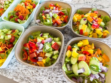 Mutfak tezgahındaki konteynırlarda hazırlanmış salata koleksiyonu. Bu sağlıklı salatalar fasulye, haşlanmış yumurta, taze sebze ve canlı renklerle dolu. Yemek planlamak için ideal.