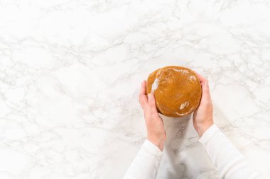 Overhead view of a portion of Classic Gingerbread Cookie Dough, freshly scooped from a mixing bowl and shaped into a round disc on a marble countertop. This step prepares the dough for wrapping and clipart