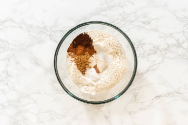 Kuru malzemelerle karıştırılmış un, tarçın, zencefil ve karanfil, canlı zencefilli kurabiyeler için hazırlandı. Bu baharatlar sıcak ve aromatik tatlar getirecek.