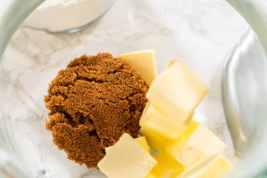 Kahverengi şeker ve tereyağı küpleri içeren cam karıştırma kabının yakından görüntüsü, Amber zencefilli kurabiye kurabiye kurabiye tarifinde krema için hazırlandı..