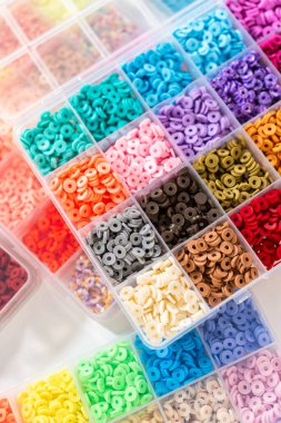 Beyaz bir masaya yerleştirilmiş çeşitli kil boncuk kutuları yaratıcı çocukların el sanatları projesini bekliyor..