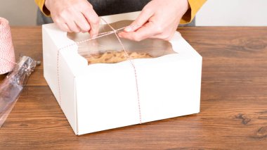 Tuzlu karamel şekerlemeleri ve zencefilli ekmek parçacıklarıyla süslenmiş zencefilli keki dikkatlice hediye etmek için açık pencereli beyaz bir kağıt bohça kek kutusuna yerleştiriyorum..