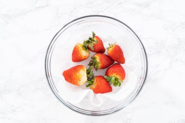 Taze yıkanmış ve kurutulmuş çilekler kağıt havluyla kaplı cam bir kasede dikkatlice düzenlenir. Atıştırmaya ya da daha fazla kullanılmaya hazır hale getirilir..