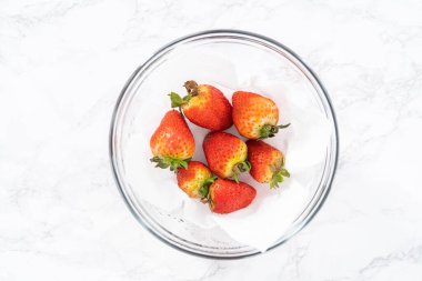 Taze yıkanmış ve kurutulmuş çilekler kağıt havluyla kaplı cam bir kasede dikkatlice düzenlenir. Atıştırmaya ya da daha fazla kullanılmaya hazır hale getirilir..