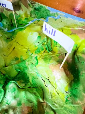 Dağlar, vadiler, nehirler, tepeler ve tasarruflar gibi çeşitli arazilerin sergilendiği yaratıcı bir okul bilim projesi. Model, eğitim amaçlı canlı renkler ve etiketler içeriyor.