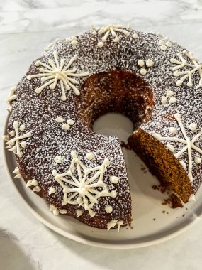 A beautifully decorated gingerbread Bundt cake adorned with powdered sugar and intricate snowflake icing designs. A festive holiday dessert perfect for winter celebrations and gatherings. clipart