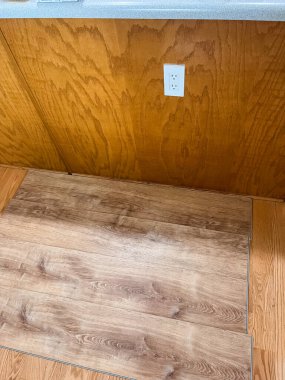 Vinil döşeme, bir evin içindeki ahşap zemine monte ediliyor. Yeni vinil tahtalar ve eski sert ahşap yüzey arasındaki zıtlığı vurgulayan yakın plan bir görünüm.