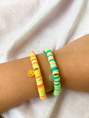 Küçük bir kız bileğinde el yapımı inci bileziğini gösteriyor. Basit ama zarif bilezik beyaz boncuklarla yaratıcılığı ve işçiliği ön plana çıkarıyor..