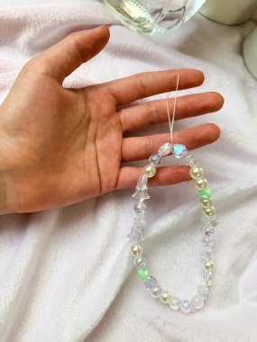 A little girl showcasing her handmade pearl bracelet on her wrist. The simple yet elegant bracelet is crafted with white beads, highlighting creativity and craftsmanship. clipart