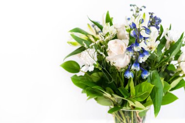 Taze beyaz güllerin ve çeşitli çiçeklerin bulunduğu büyüleyici bir buket, zarif bir vazoda düzenlenmiş, zamansız bir güzellik yayıyor..