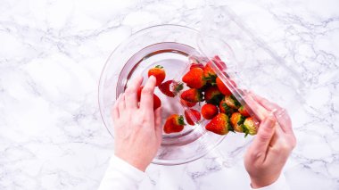 Düz yatıyordu. Olgun çilekler, depolama veya tüketimden önce temizlik ve uzun ömürlü olmak için meyveyi yıkamada bir adım olarak büyük bir bardakta karıştırma kabında suya gömülür..