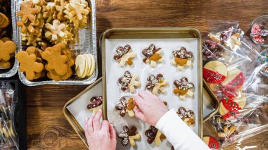 Düz yatıyordu. Dikkatlice paketlenmiş Noel kurabiyeleri, çikolataya batırılmış, ezilmiş fındık serpiştirilmiş, ve şeffaf selofan ambalajla sunulmuş..