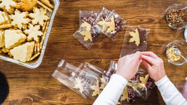 Düz yatıyordu. Dikkatlice paketlenmiş Noel kurabiyeleri, çikolataya batırılmış, ezilmiş fındık serpiştirilmiş, ve şeffaf selofan ambalajla sunulmuş..