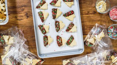 Düz yatıyordu. Dikkatlice paketlenmiş Noel kurabiyeleri, çikolataya batırılmış, ezilmiş fındık serpiştirilmiş, ve şeffaf selofan ambalajla sunulmuş..