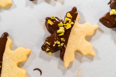 Çikolataya batırılmış yıldız şeklinde tatil kurabiyeleri ve ezilmiş şam fıstığı serpiştirmek. Parşömen kağıdına yerleştirilmiş..