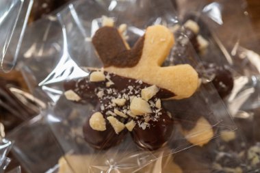 Dikkatlice paketlenmiş Noel kurabiyeleri, çikolataya batırılmış ve şeffaf selofan ambalajla sunulmuş, bayram hediyesi olarak mükemmel..