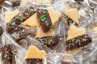 Dikkatlice paketlenmiş Noel kurabiyeleri, çikolataya batırılmış ve şeffaf selofan ambalajla sunulmuş, bayram hediyesi olarak mükemmel..
