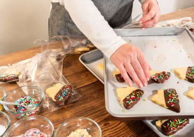 Dikkatlice paketlenmiş Noel kurabiyeleri, çikolataya batırılmış ve şeffaf selofan ambalajla sunulmuş, bayram hediyesi olarak mükemmel..