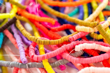 Beyaz bir masadaki renklere göre düzenlenmiş canlı bir kil boncuk koleksiyonu genç zanaatkarlara kendi eşsiz bileziklerini yapmaları için ilham vermeye hazır..