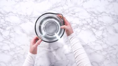 Cam ölçme bardakları suyla doludur, sıralanır ve dikkatli bir şekilde taze çilek yıkamada kullanılmaya hazırdır, kusursuz ve eksiksiz temizliği sağlar..