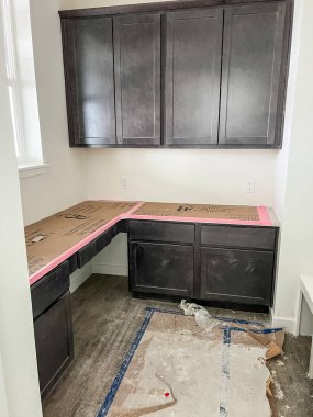 Parker, Colorado, ABD-11 Ocak 2023-A çalışma alanı karanlık dolaplar ve inşaat sırasında koruyucu kağıtlarla kaplı bir tezgah. Oda döşemede kısmen ilerleme gösteriyor