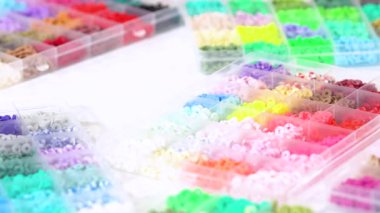 Parlak renkli balçık boncuklarından oluşan geniş bir koleksiyonu bölümlere ayıran eller, karmaşık malzemelerin güzelliğini ve çeşitliliğini vurguluyor.