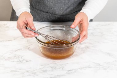 Glass bowl containing wet ingredients for Pale Gingerbread Cookies with Subtle Spice Flavor, including maple syrup and eggs. Ready to be mixed together. clipart