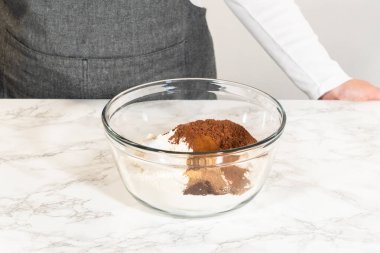 İçinde kakao tozu, baharat ve un içeren kuru çikolatalı zencefilli kurabiye hamuru bulunan bir kase mermer tezgahta karıştırılmaya hazır..