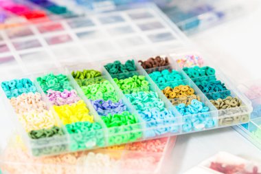 Beyaz bir masaya yerleştirilmiş çeşitli kil boncuk kutuları yaratıcı çocukların el sanatları projesini bekliyor..