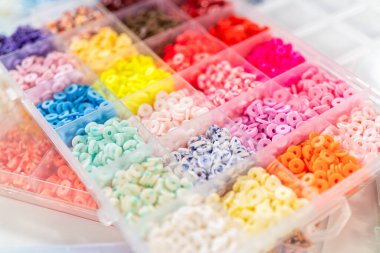 Beyaz bir masaya yerleştirilmiş çeşitli kil boncuk kutuları yaratıcı çocukların el sanatları projesini bekliyor..