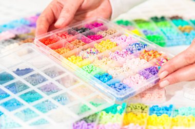 Beyaz bir masaya yerleştirilmiş çeşitli kil boncuk kutuları yaratıcı çocukların el sanatları projesini bekliyor..