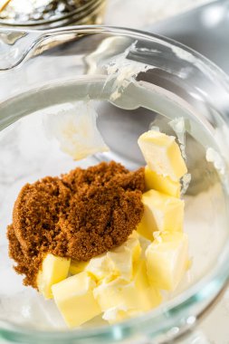 Karıştırma kabına tereyağı ve esmer şeker ekleniyor. Çikolatalı zencefilli kurabiye kurabiyesi için anahtar malzemeler. Bunlar çikolatayı tamamlayan kremalı bir doku ve derin bir tatlılık sağlar.