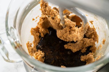 Kalın, kremalı tereyağı ve şeker karışımı karıştırma kabında. Karıştırıcı küreği bileşenleri bir araya getirerek birleşik bir karışım oluşturuyor..